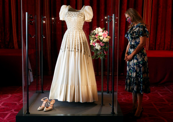 Britain's Princess Beatrice of York stands alongside her wedding dress, which was originally worn by Britain's Queen Elizabeth in the 1960s